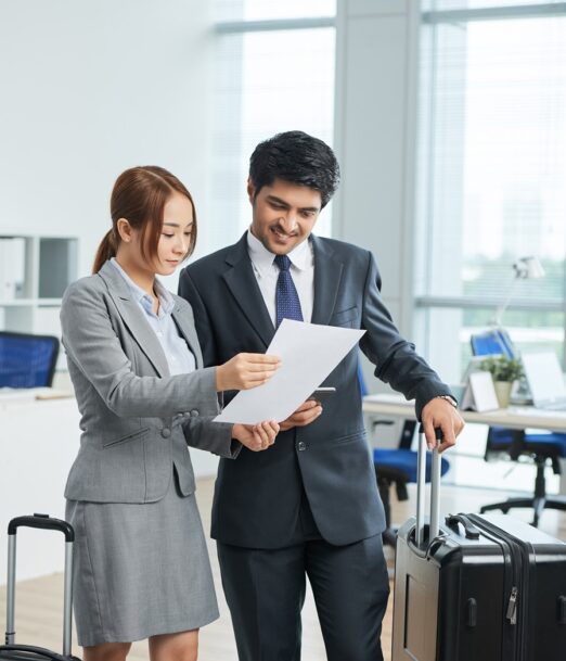 man-woman-business-suits-standing-office-with-suitcases-looking-together-document (1)